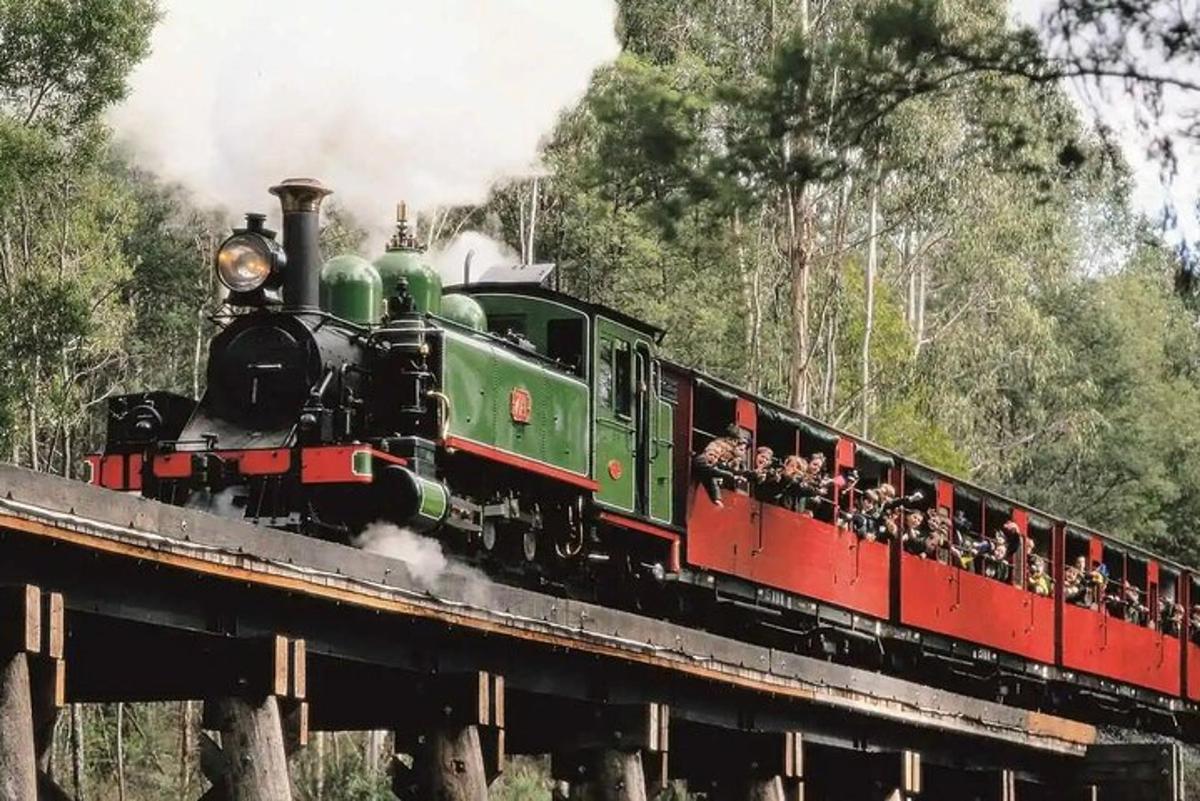 un treno verde e rosso su un ponte con passeggeri