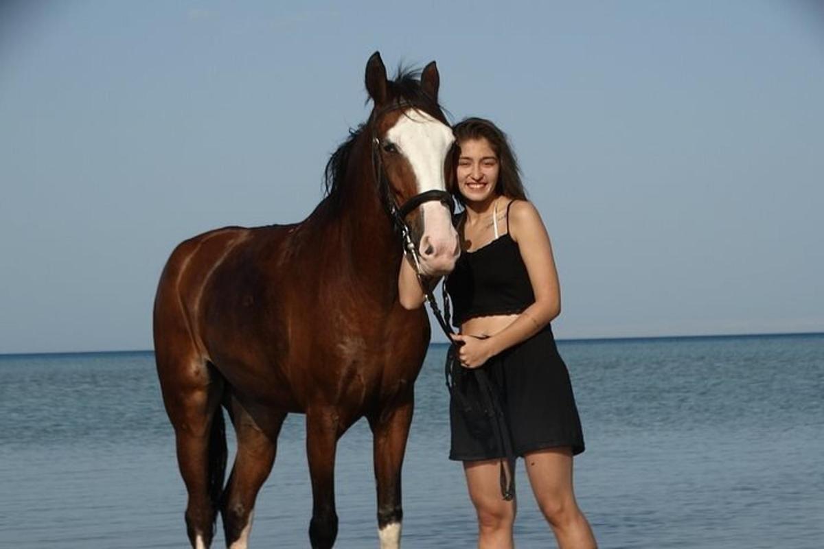 una donna in piedi accanto a un cavallo sulla spiaggia