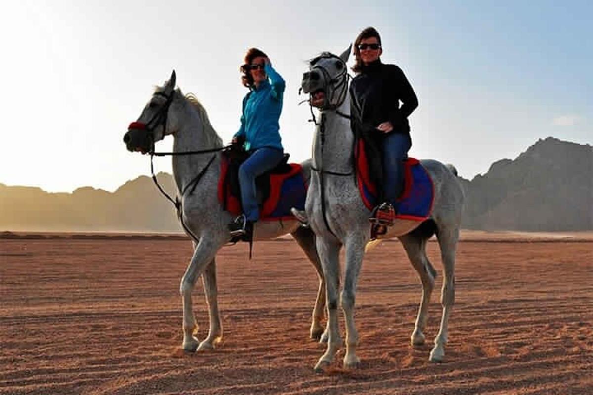 dues persones muntant a cavall al desert