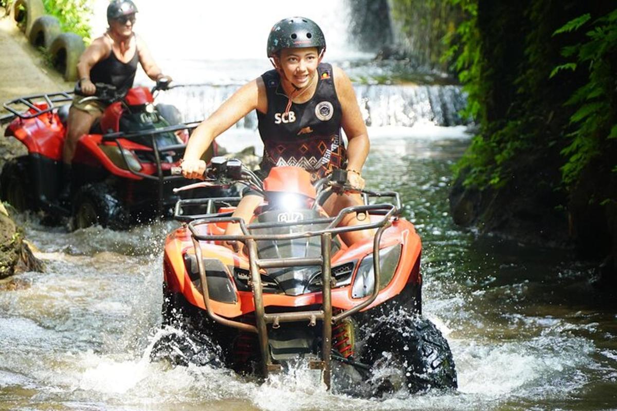 een man die op een ATV door een rivier rijdt
