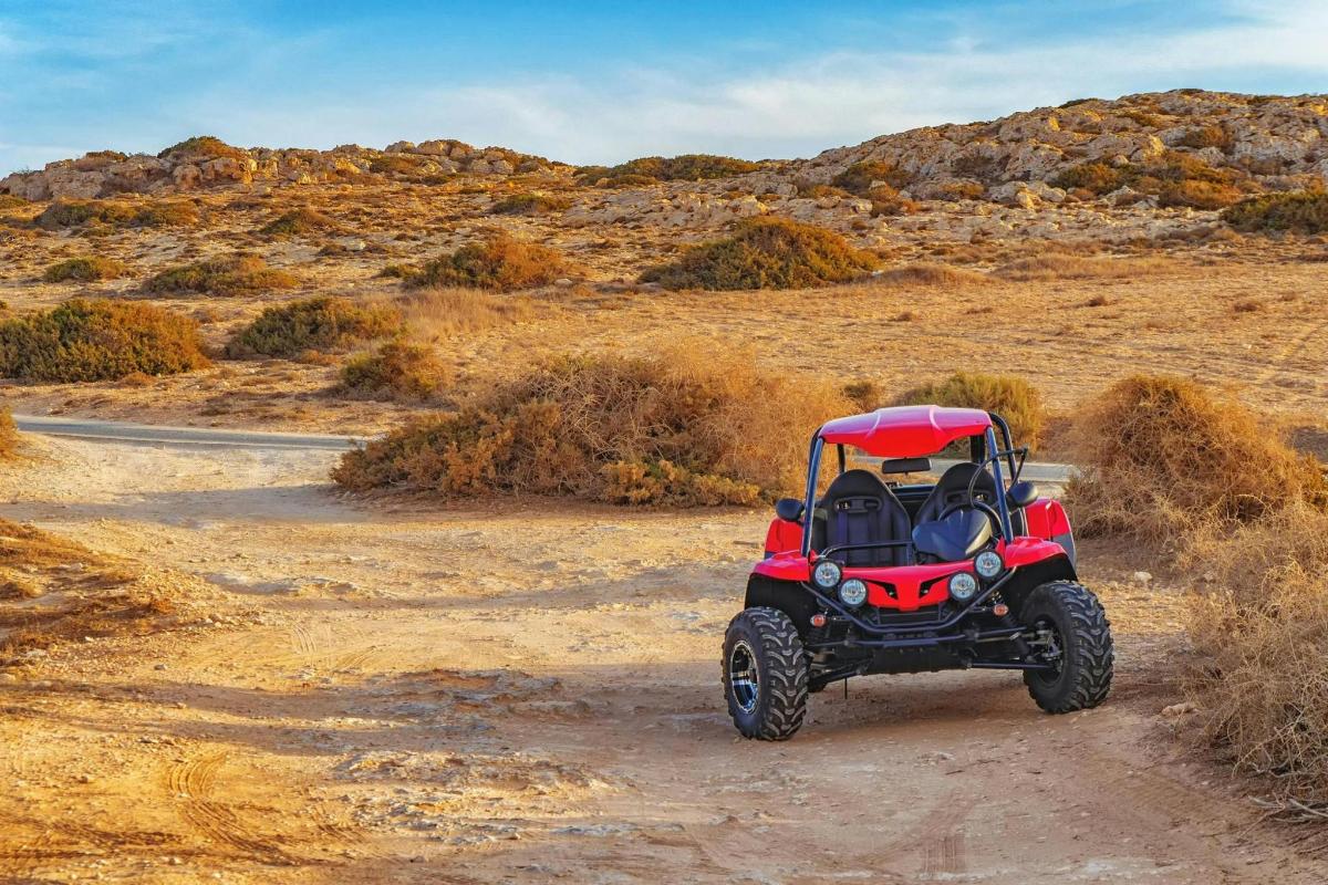 un quad vermell conduint per una carretera de terra
