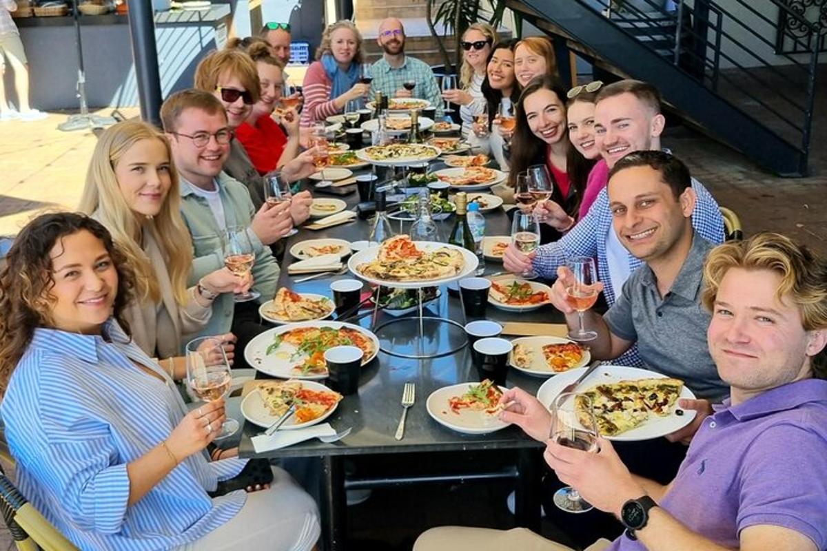 hópur fólks situr við borð og borðar pizzu