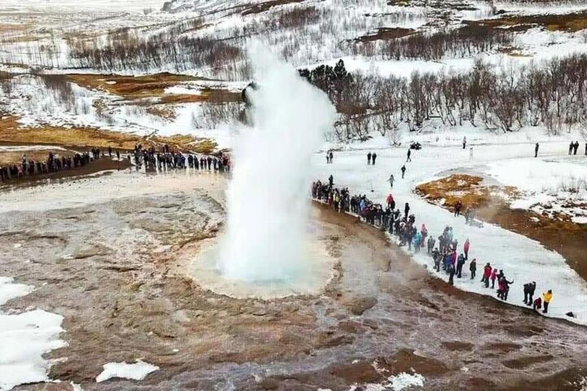 ryhmä ihmisiä seisoo geysirin ympärillä