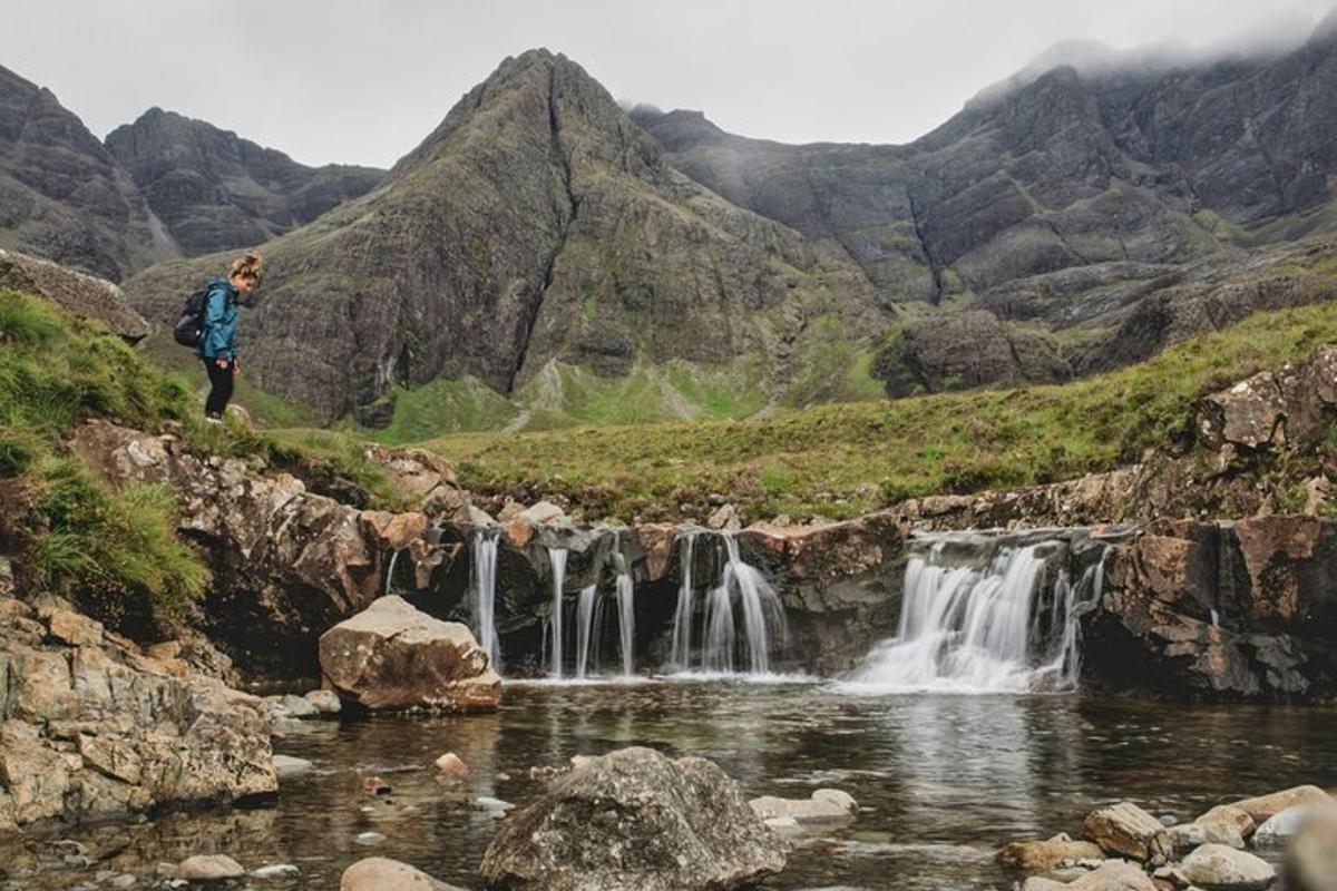 a man standing on a hill next to a waterfall