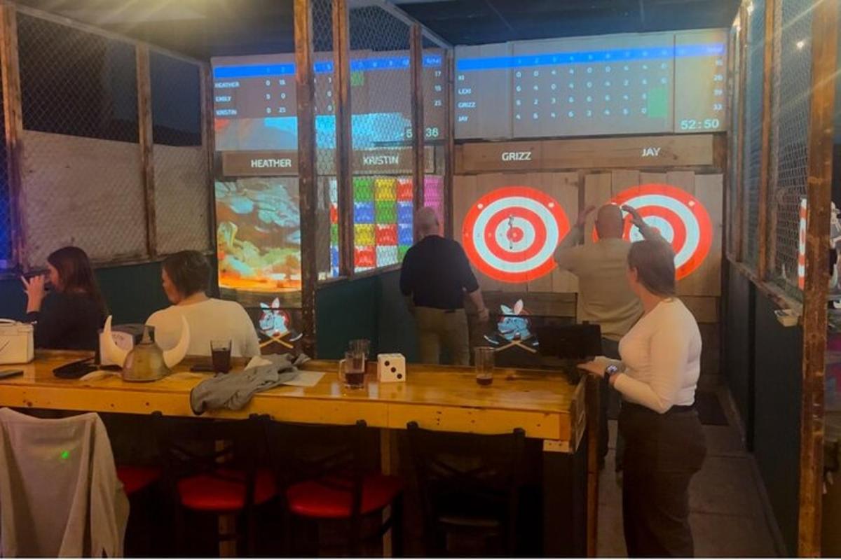 a group of people standing around a table with darts