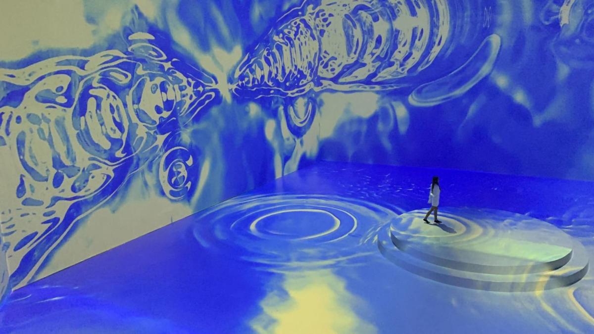 a person standing in front of a painting of two jellyfish