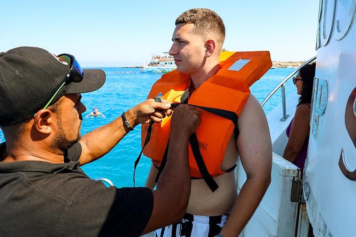 oranžis päästevestis meest abistab paadis olev mees