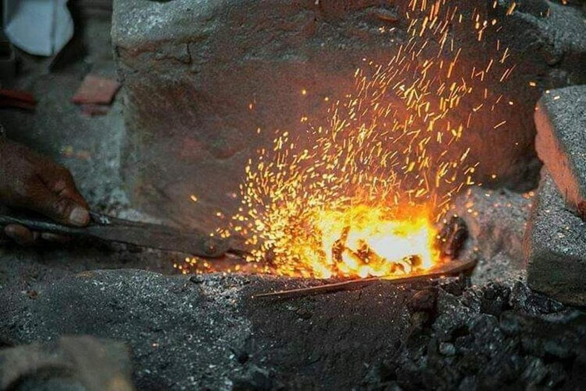 seseorang menggunakan sepasang penyepit di atas api