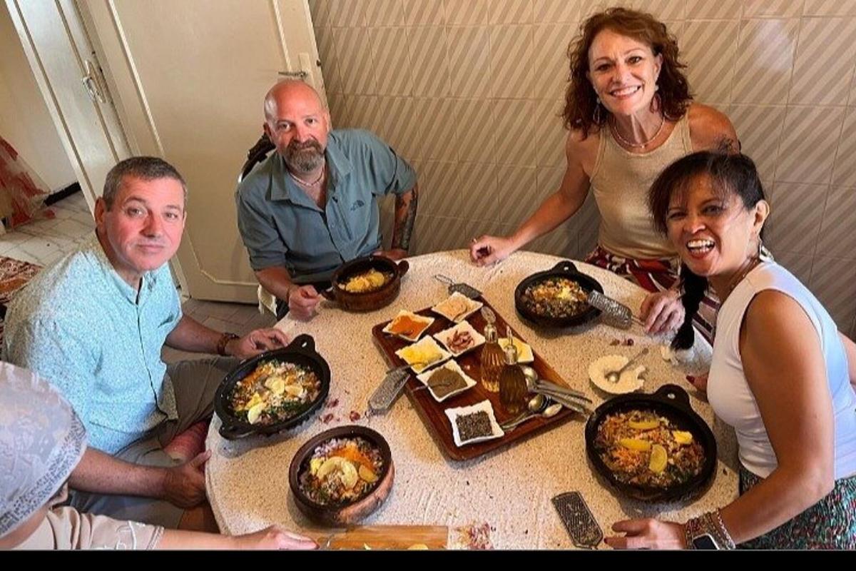 bir masanın etrafında yemek yiyen bir grup insan