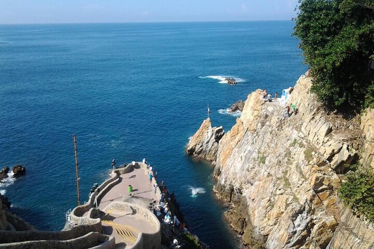 a group of people standing on a cliff near the ocean