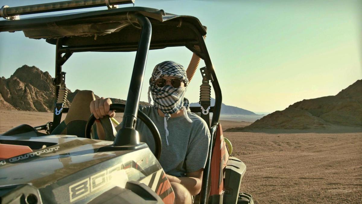 un home assegut en un vehicle al desert