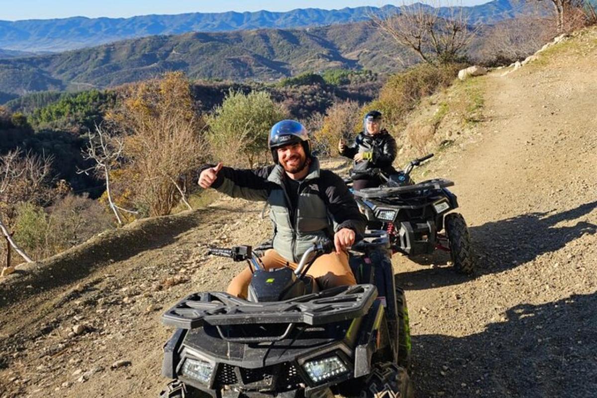 dues persones en quads per un camí de terra