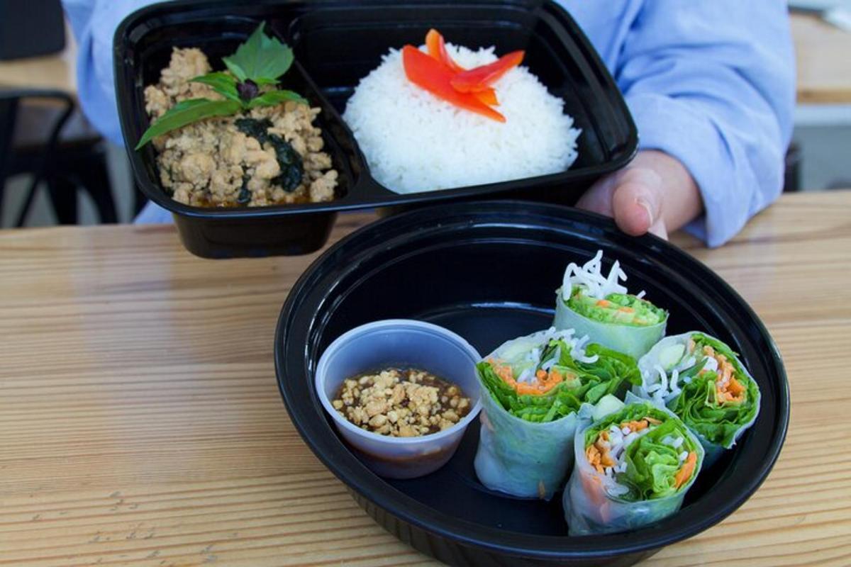 a lunch box with sushi and rice on a table
