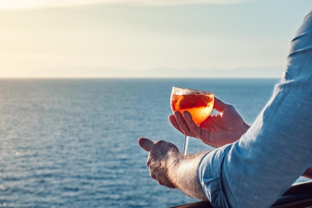 muž držící sklenici vína s výhledem na oceán