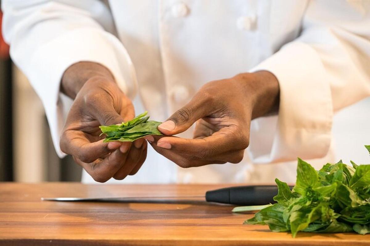 a chef holding a bunch of greens on a table