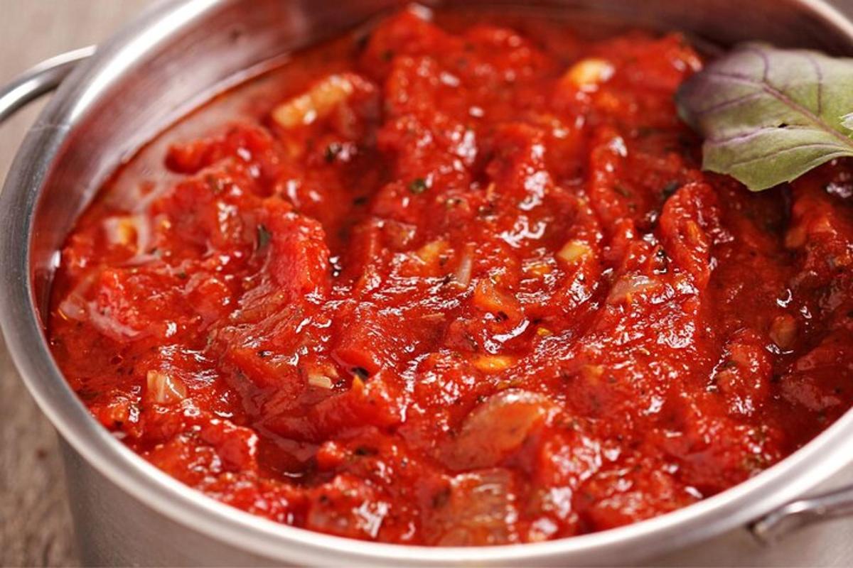a pot of pasta with tomato sauce and a basil leaf