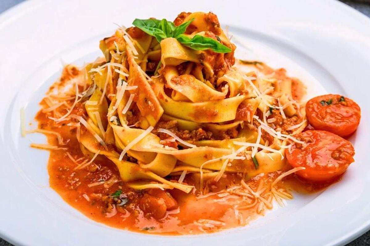 a white plate of pasta with sauce and cheese