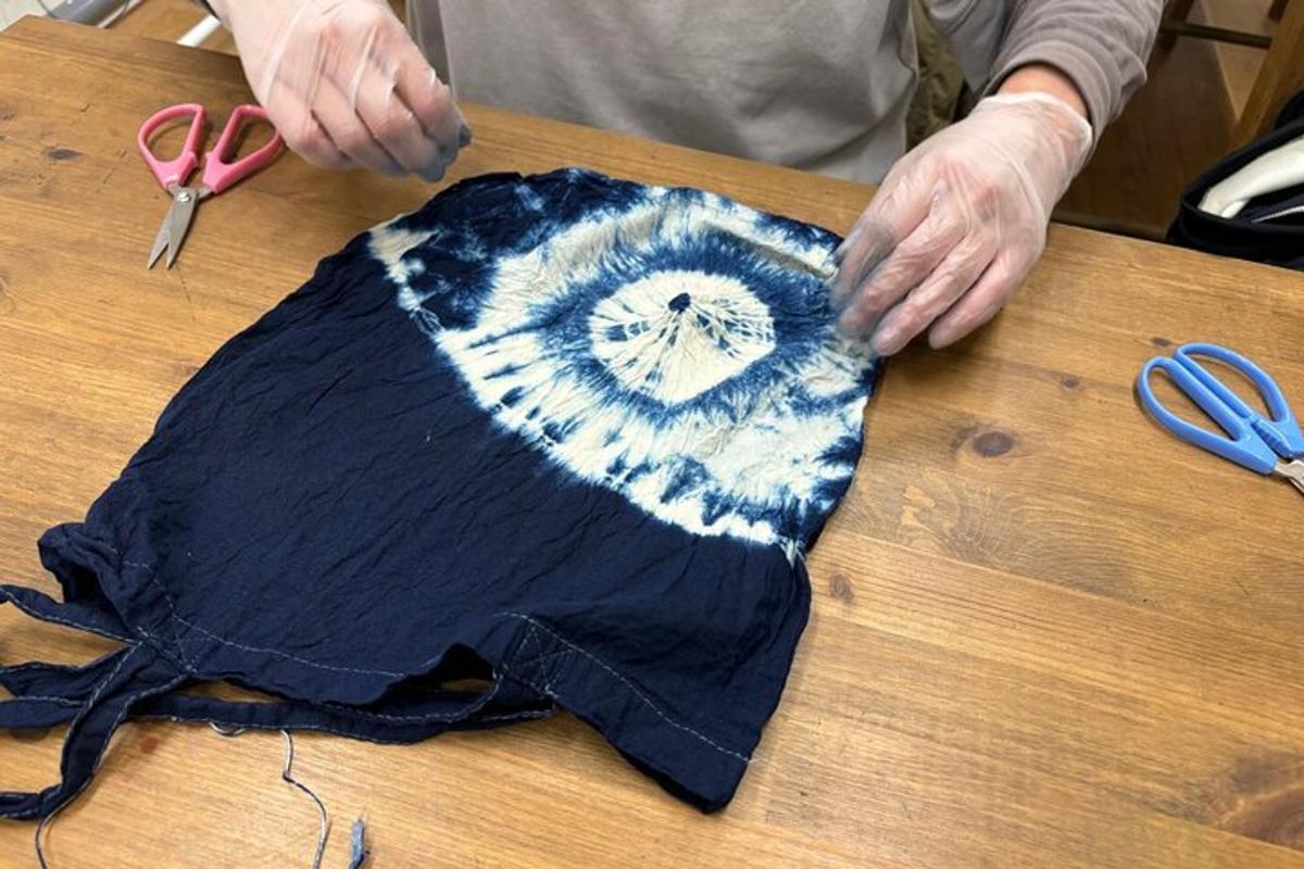 osoba tnąca kawałek materiału na stole nożyczkami