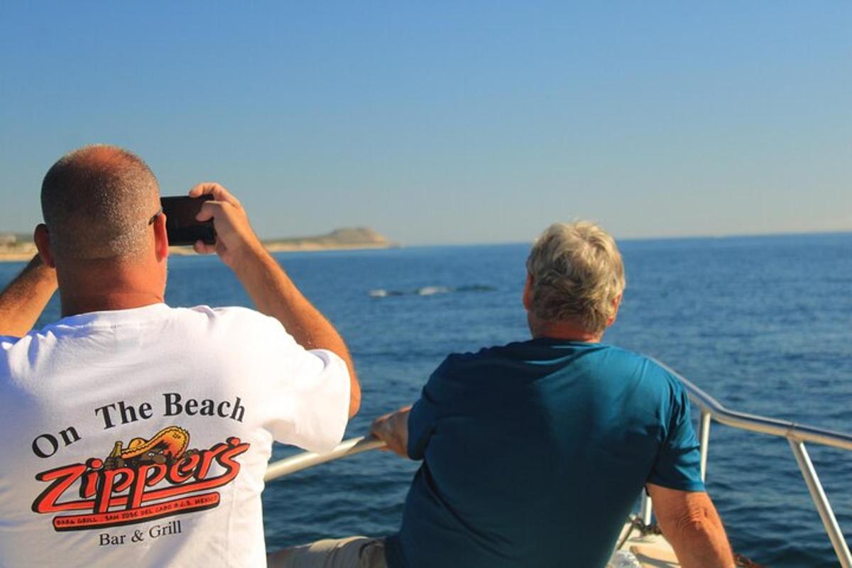 two men on a boat taking a picture of the ocean