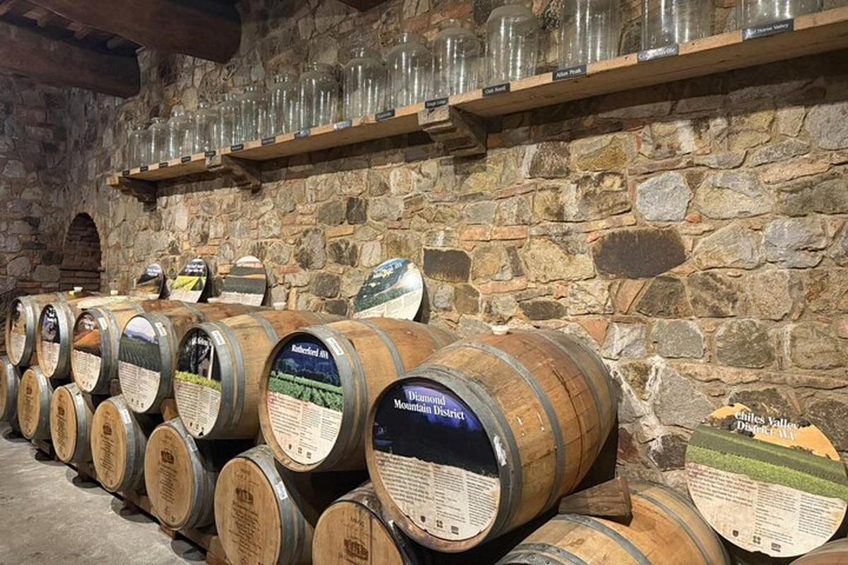 Una fila de barriles de vino alineados contra una pared de piedra