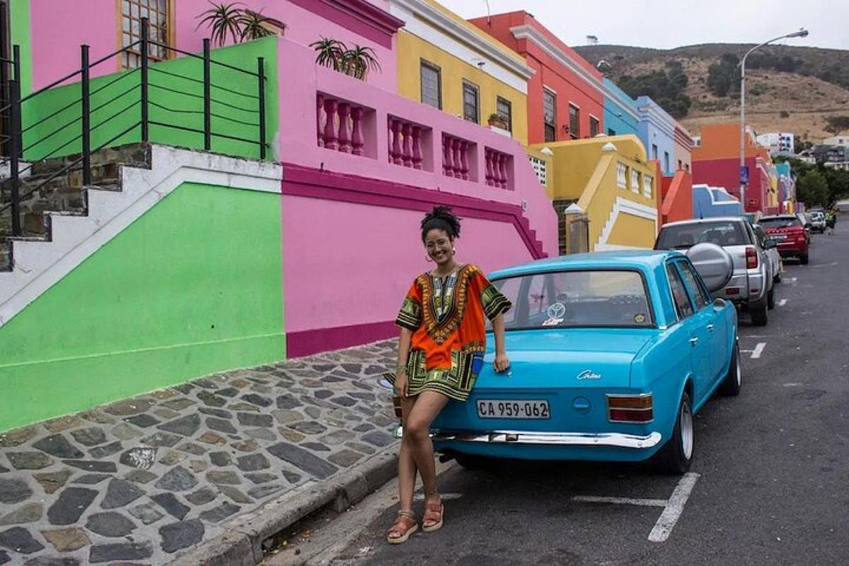 a woman standing next to a blue car on a street