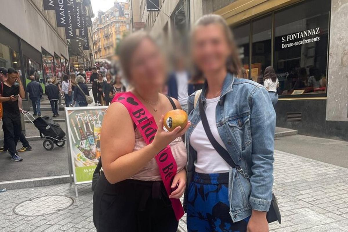 Két nő áll egy városi utcán, a kezében egy narancs