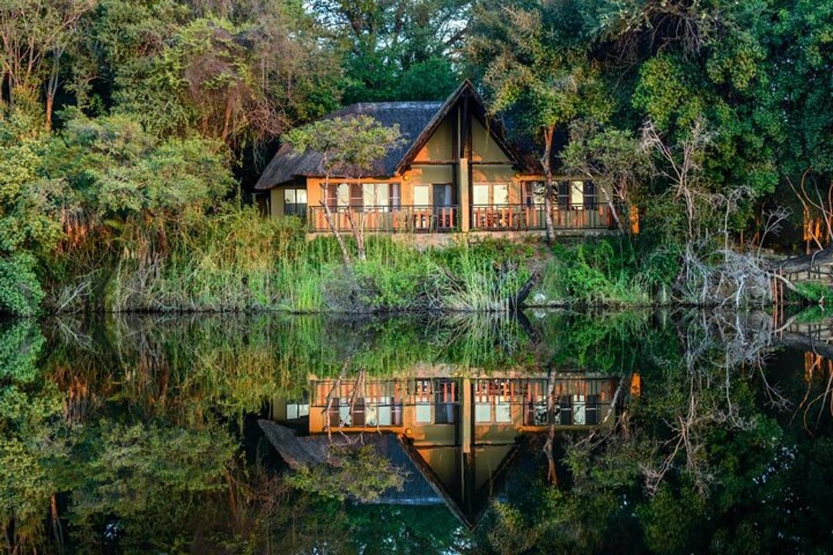 a house on the shore of a lake with its reflection in the water