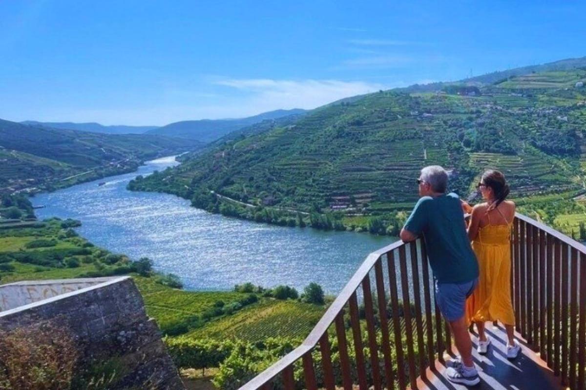 muž a žena stojící na balkóně s výhledem na řeku