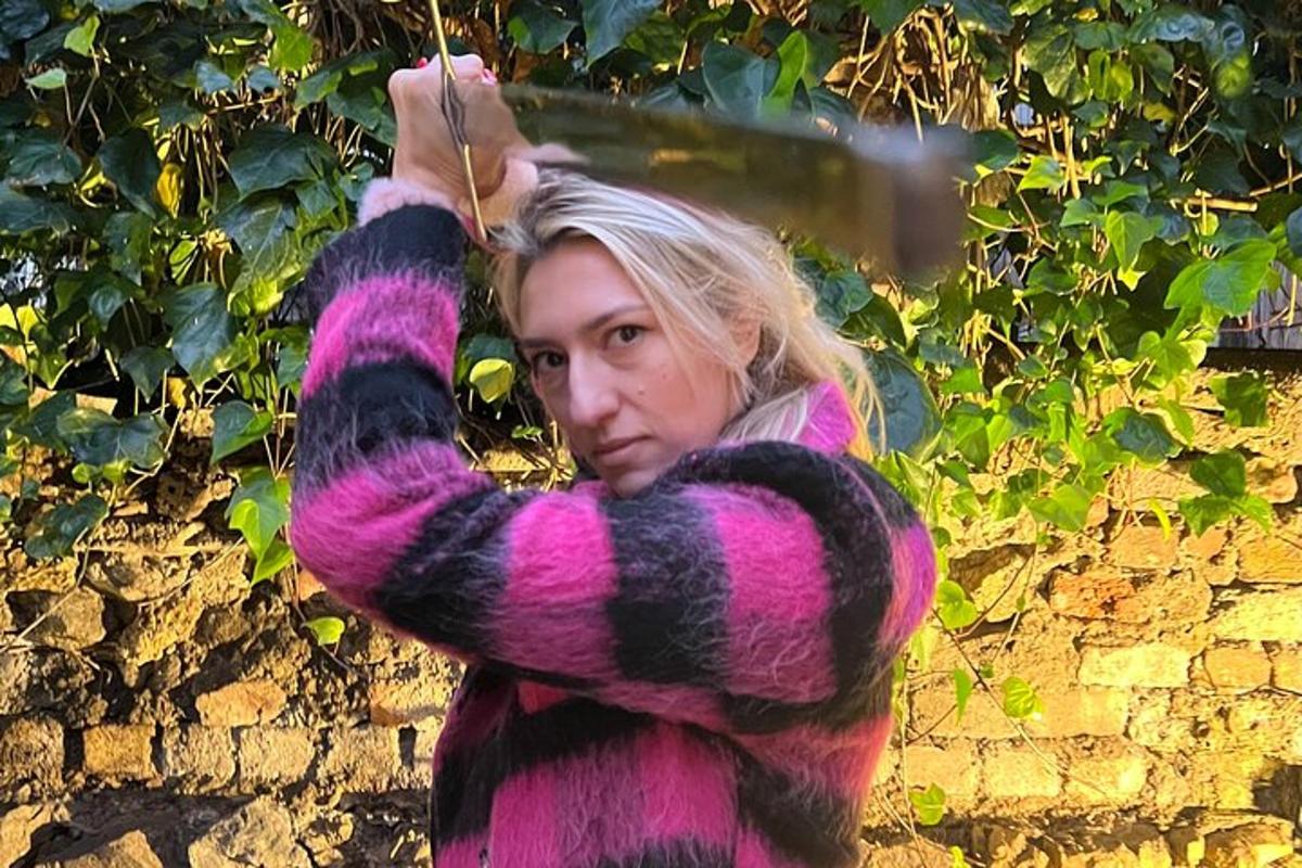 una donna con un maglione viola e nero che tiene in mano un ombrello