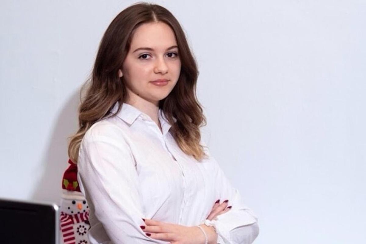 una donna con una camicia bianca in piedi davanti a un computer portatile