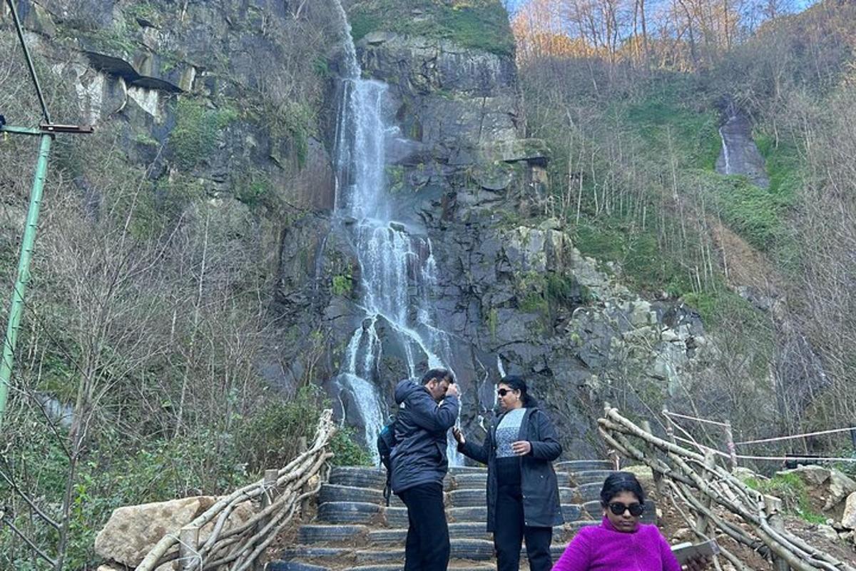 two people standing on stairs in front of a waterfall