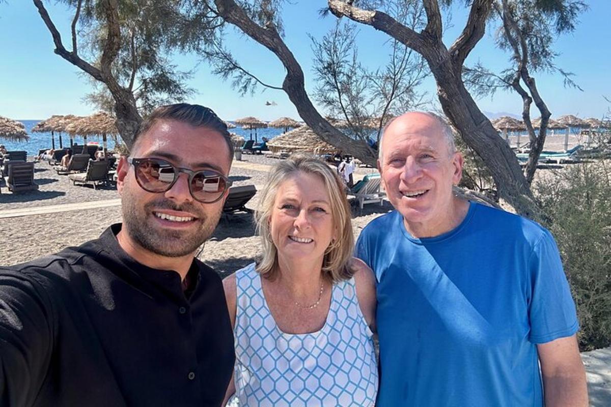 two men and a woman posing for a picture at the beach