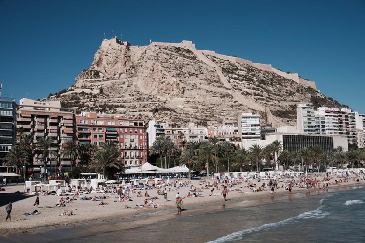 um grupo de pessoas em uma praia com uma montanha