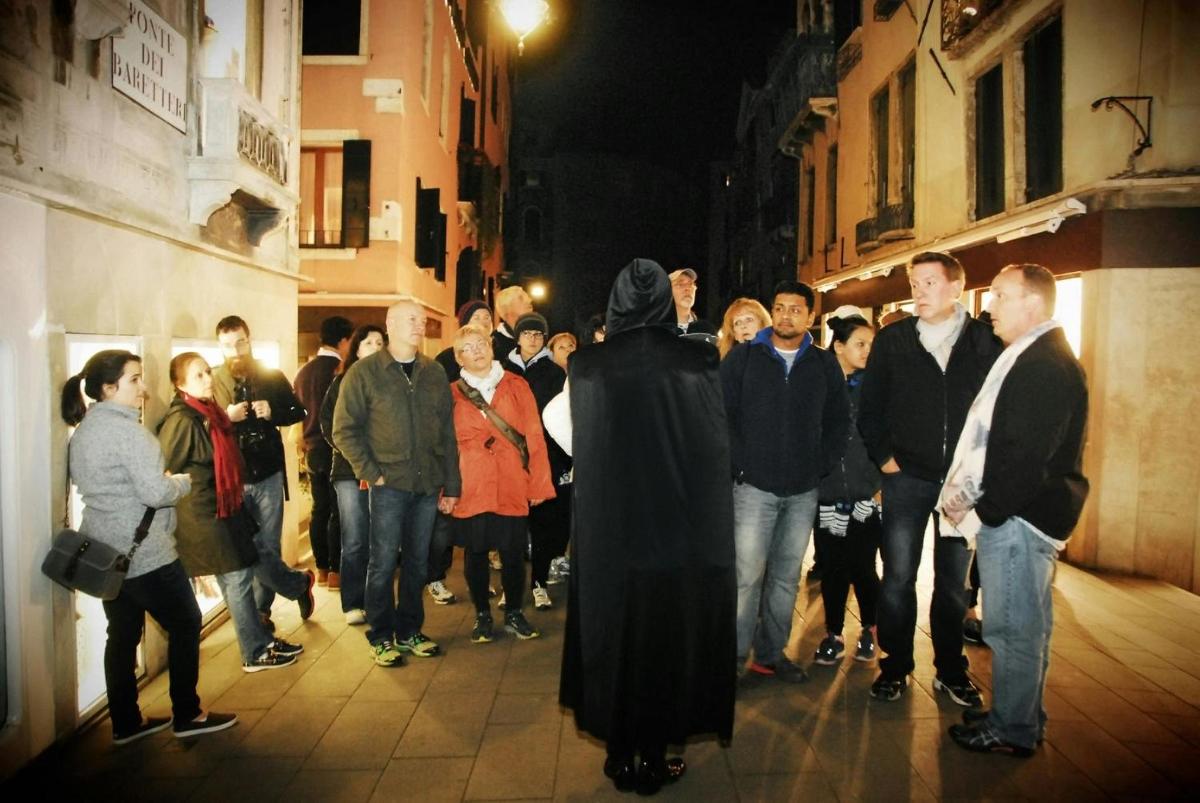 Un grupo de personas paradas en una calle por la noche.