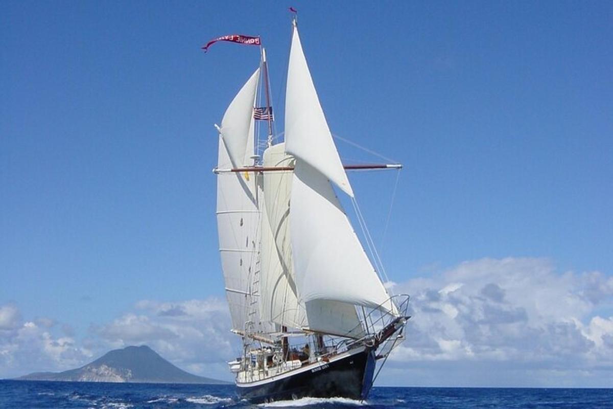 a sail boat with white sails in the ocean