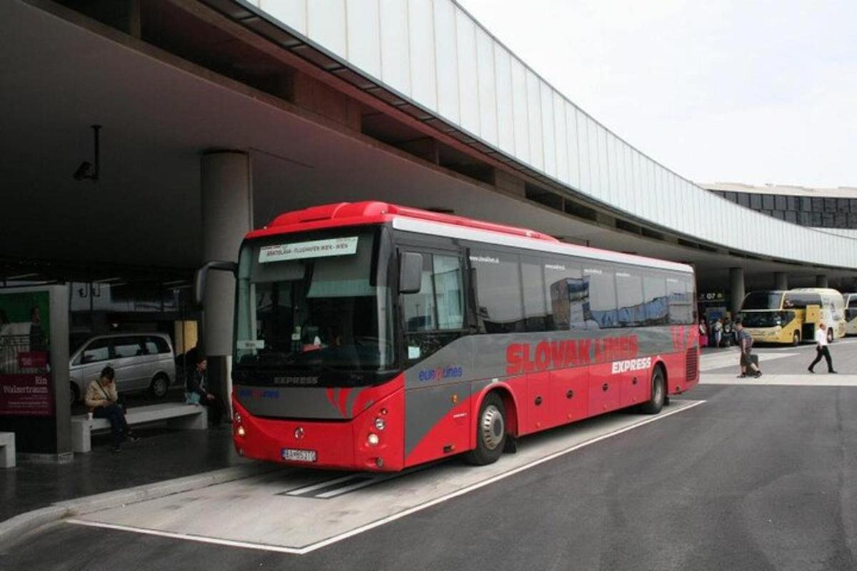 um ônibus vermelho está estacionado ao lado de um prédio
