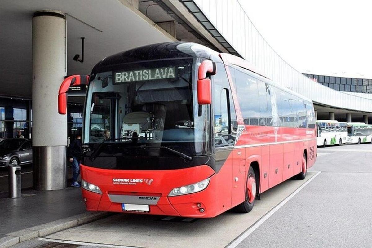 Un autobús rojo está estacionado al lado de un edificio