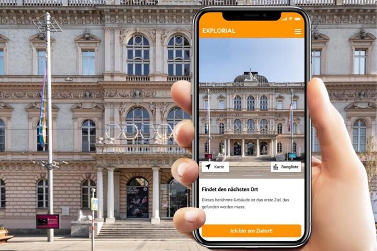 oseba, ki drži mobilni telefon pred stavbo