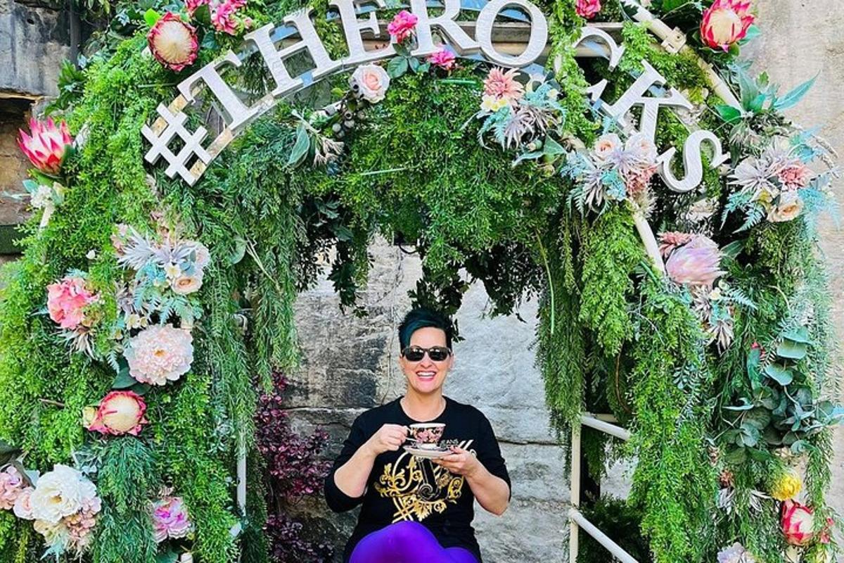a woman sitting in front of a floral arch
