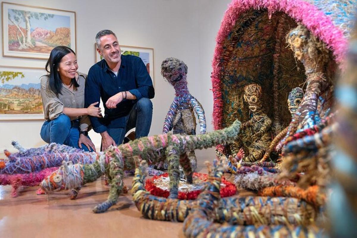 a man and woman sitting in front of a display of art