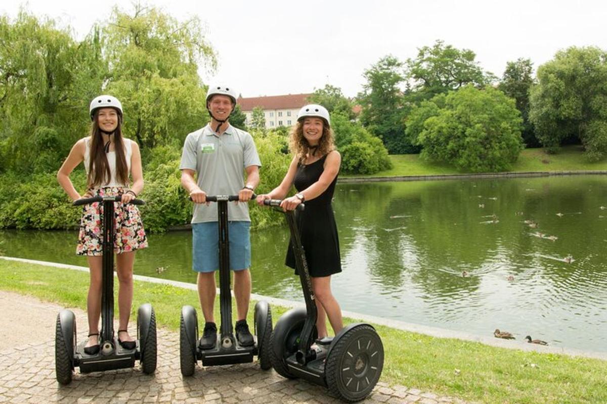 a man and two women riding on segways by a lake