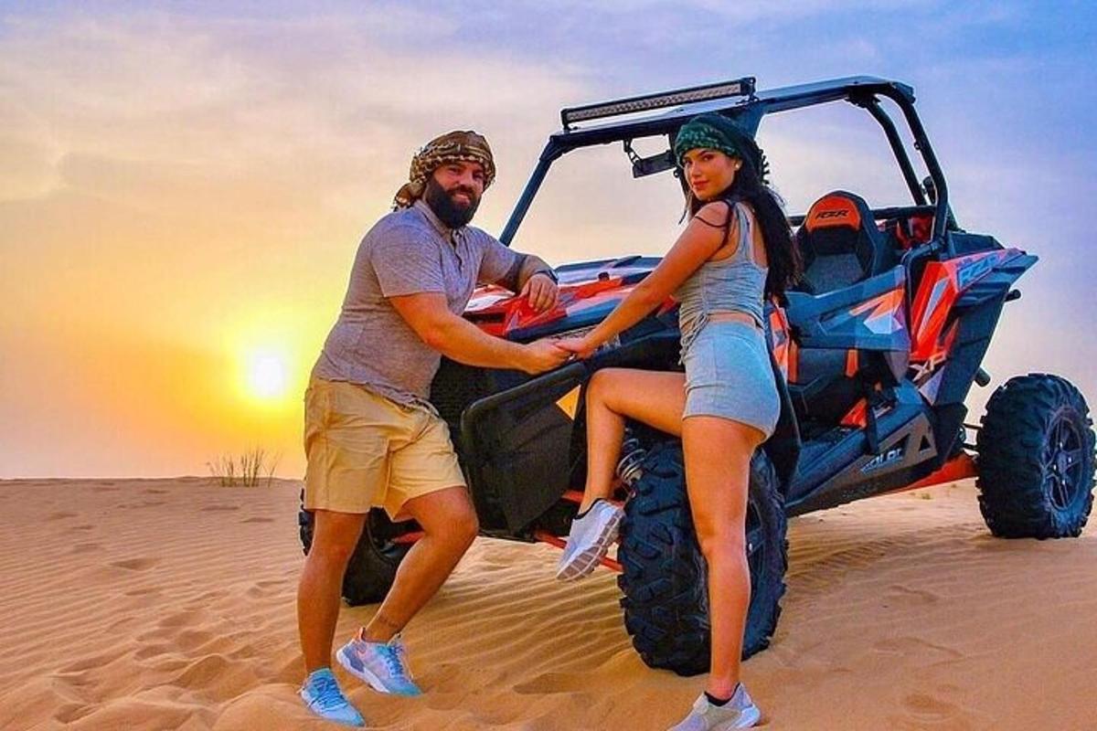um homem e uma mulher parados em um jipe no deserto