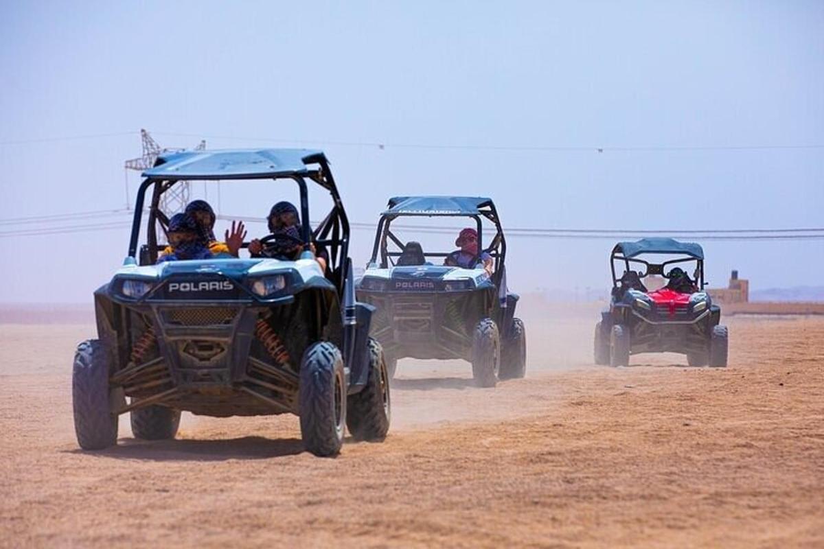 土のフィールドでATVに乗る3人