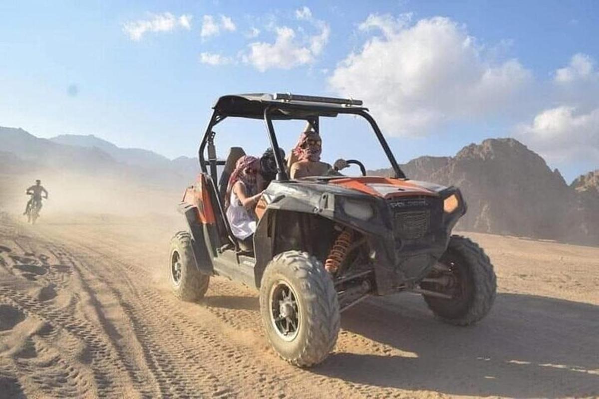 um grupo de pessoas andando de jipe no deserto