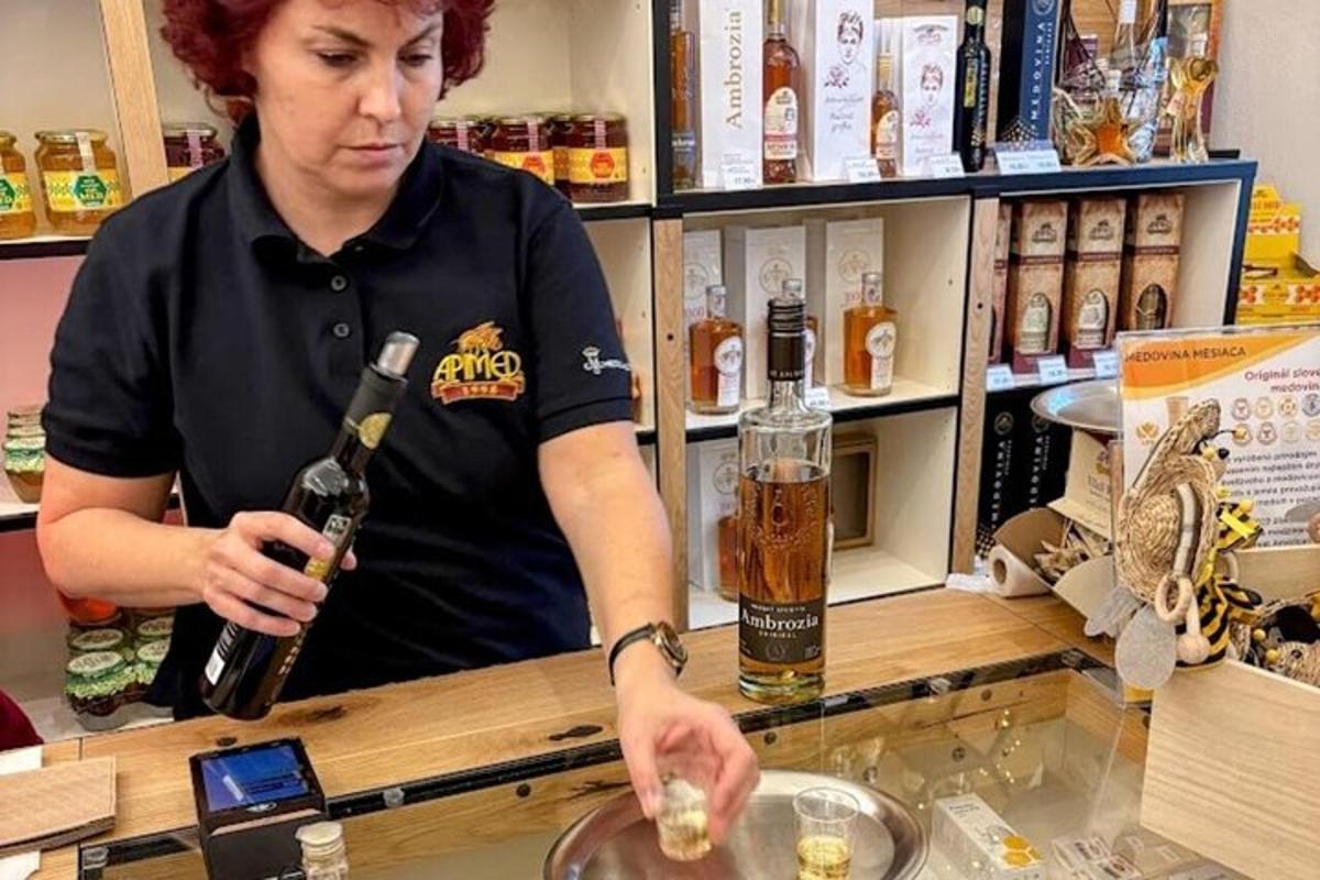 una donna in piedi dietro un bancone con una bottiglia di vino