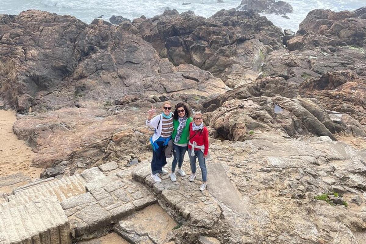 a group of people standing on the rocks near the ocean