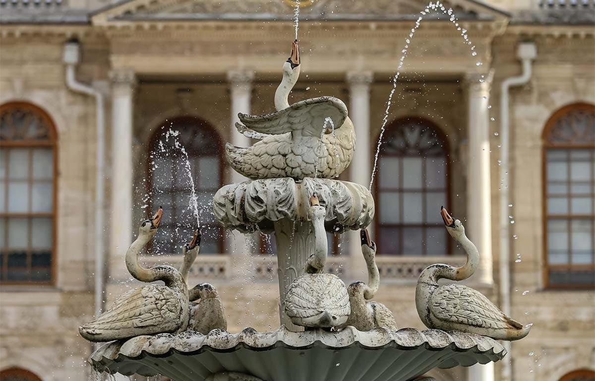 Una fuente con pájaros frente a un edificio.