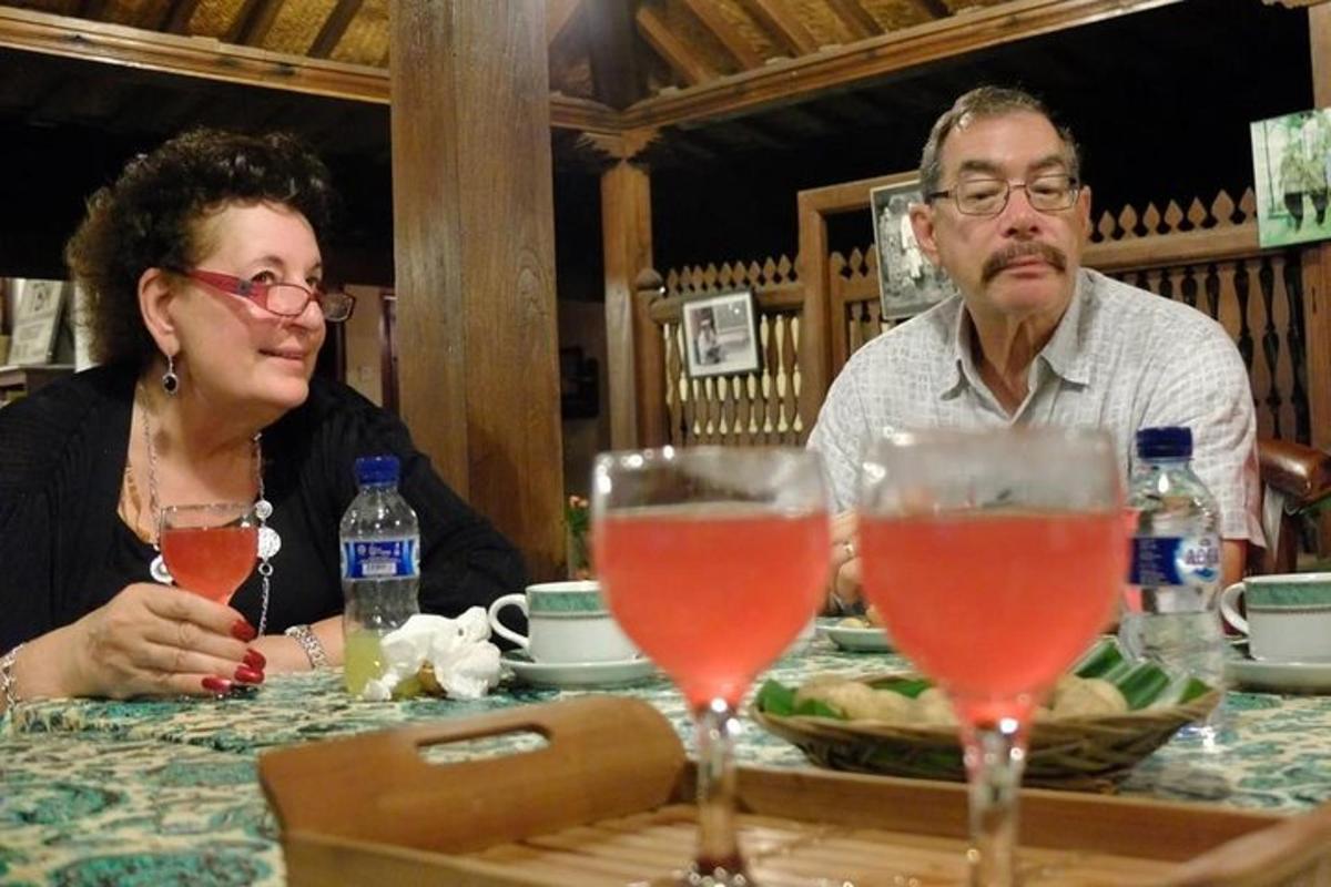 moški in ženska sedita za mizo z vinskimi kozarci