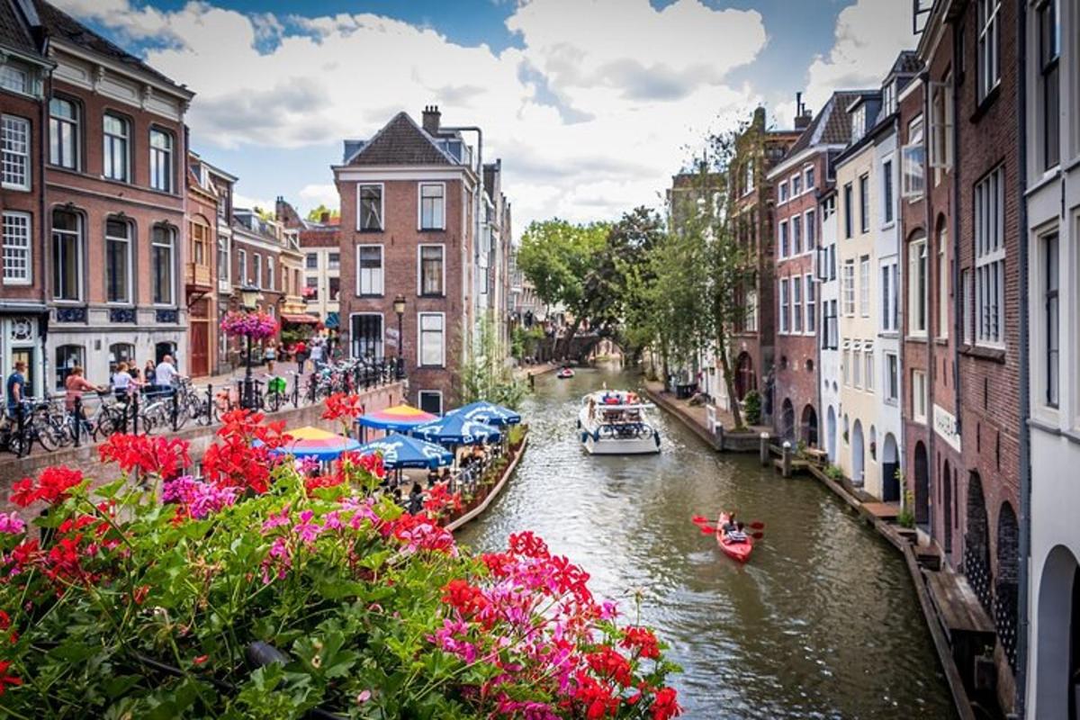 a group of boats in a canal with buildings and flowers