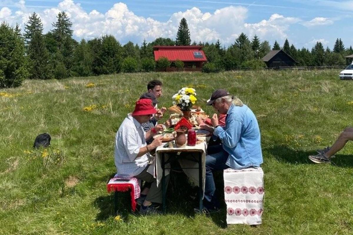 grupp inimesi, kes istuvad põllul laua taga